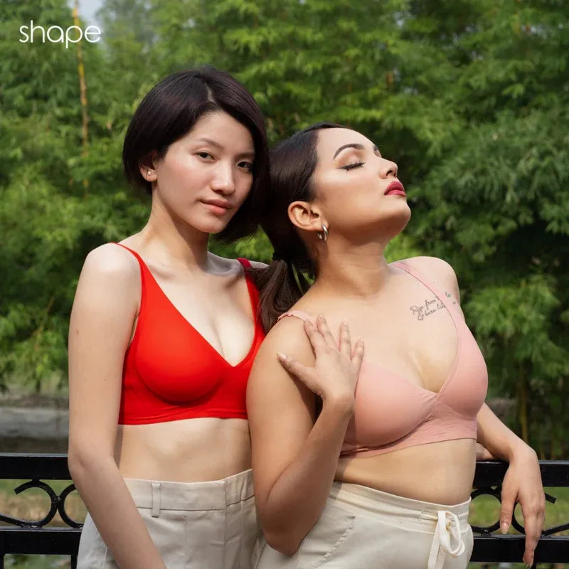 Two models wearing red and blush SHAPE Plunge Lite bras outdoors