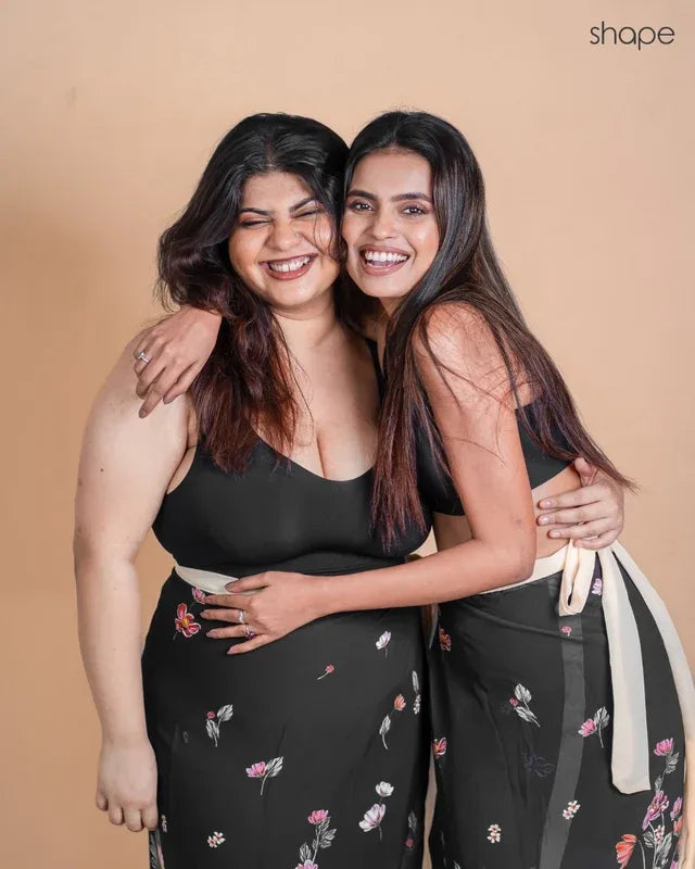 Two models wearing black SHAPE Seamless Contour Bras with printed sarees