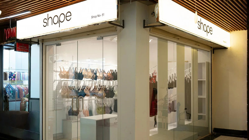 Wide-angle interior of SHAPE Lingerie Banani with lounge seating, bra racks and packaged basics on shelves